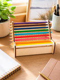 Personalisierter Holz-Stiftehalter inklusive bunter Stifte auf einem Schreibtisch als Geschenk zur Einschulung.